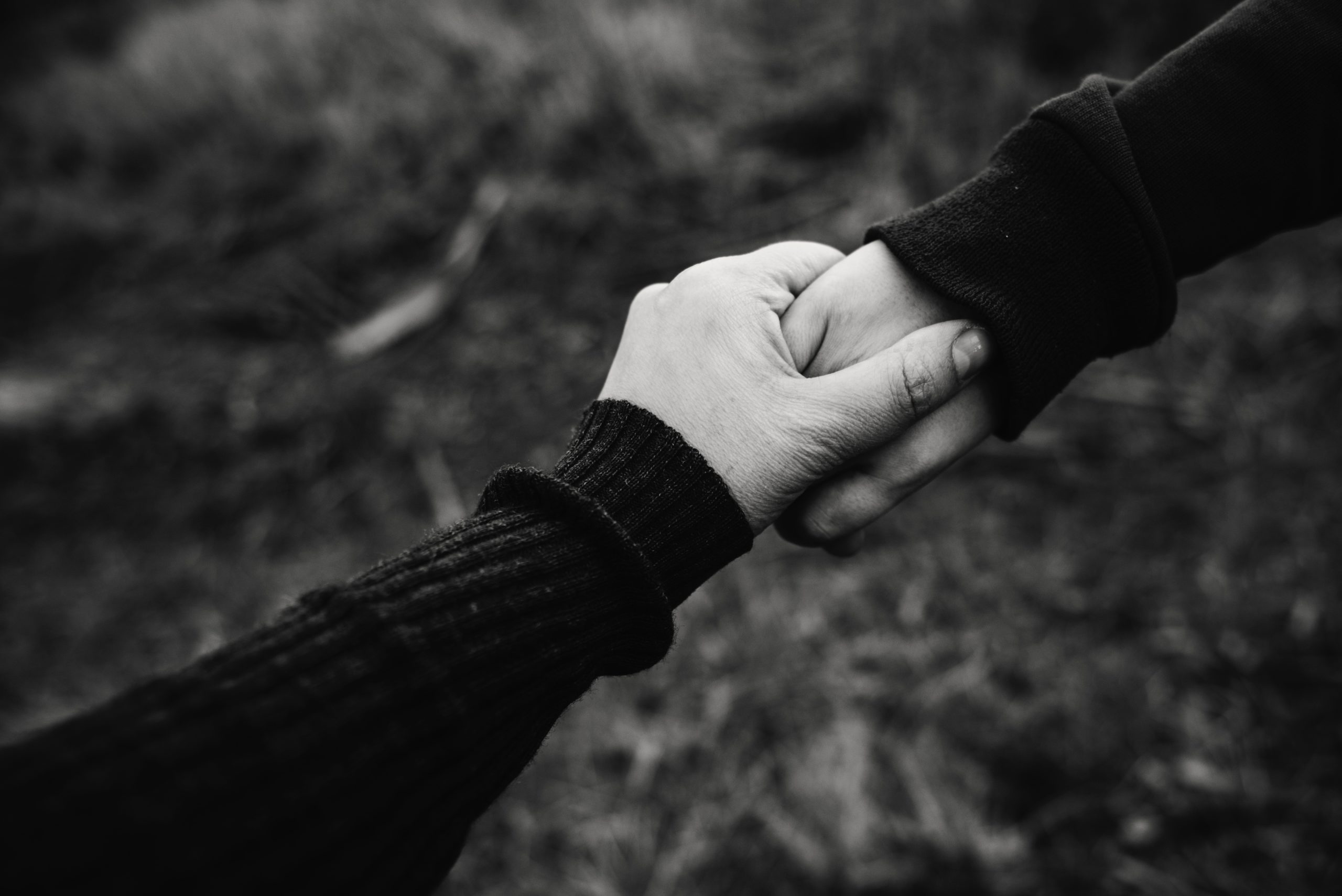 Black and white photo of two hands holding onto the other - It is okay to realize some friendships only suit you in certain seasons of your life - here are the steps you can take to let go of a friendship.