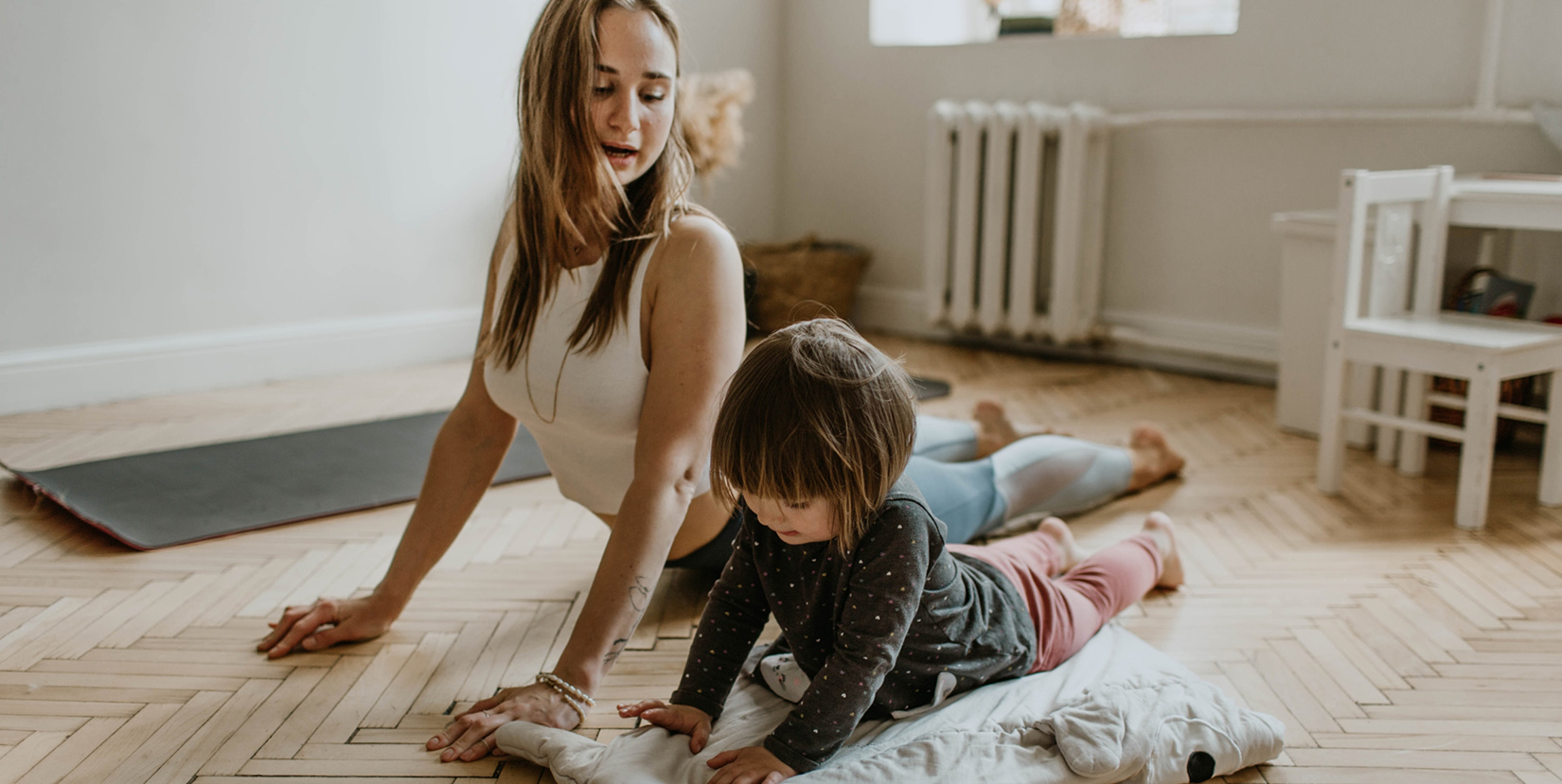 Mom stretching at home with child - Social distancing can bring feelings of anxiety and uncertainty, especially when you’re alone with your thoughts - here's how you can stay sane right now!